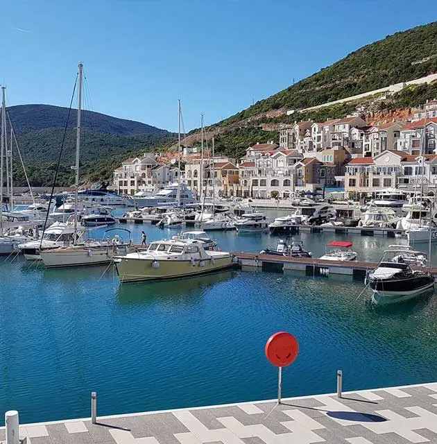 Yachthafen mit Booten auf der Halbinsel Luštica, umgeben von Hügeln und mediterraner Bebauung.