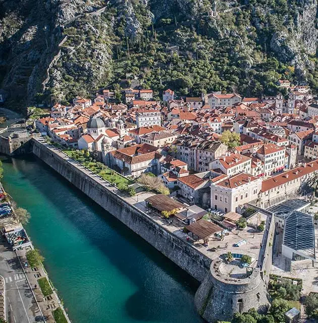 Altstadt von Kotor mit Stadtmauer, roten Dächern und Blick auf die Bucht.