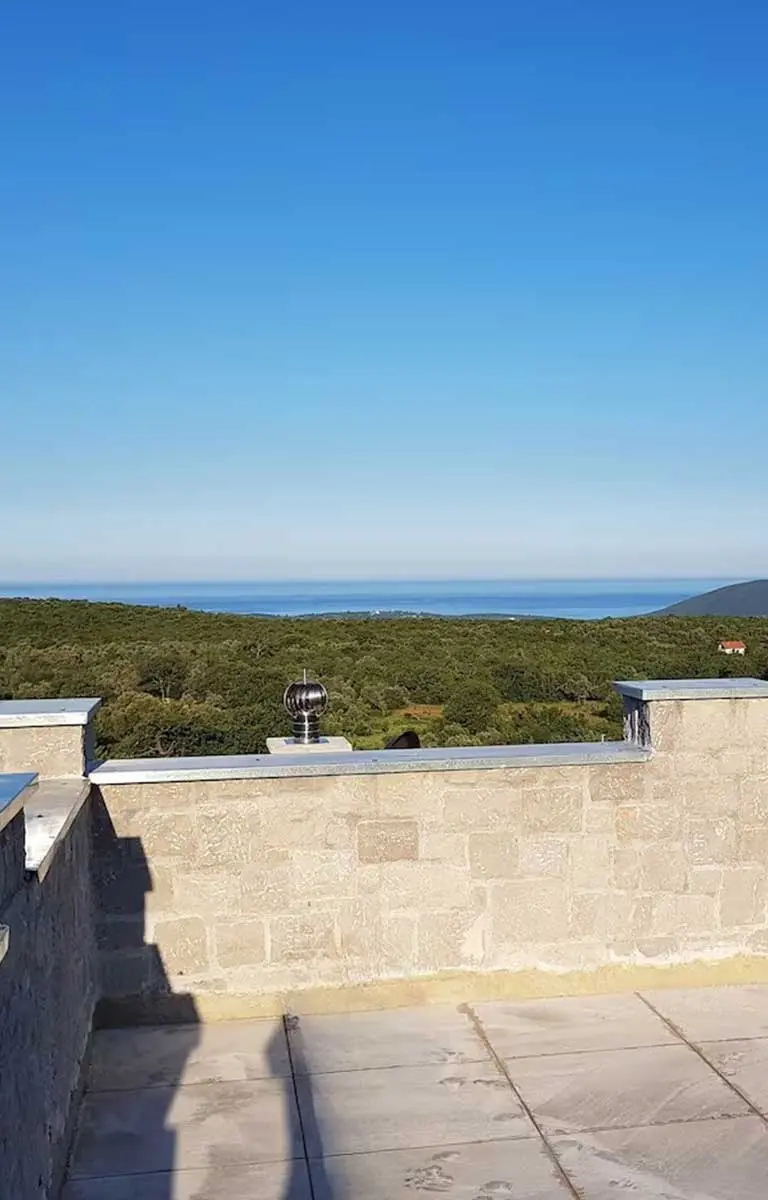 Ausblick vom Turm-Apartment auf grüne Hügel und das Adriatische Meer unter blauem Himmel