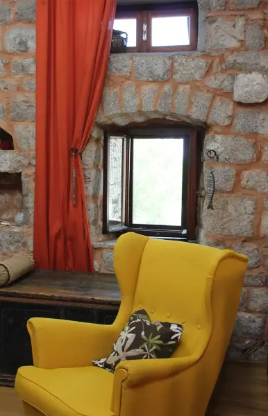 Gem&uuml;tliche Leseecke mit gelbem Sessel, Steinwand und kleinem Fenster