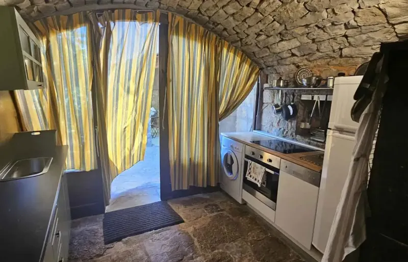 Kleine K&uuml;che mit Steinbogen, Herd, Sp&uuml;le und Vorhang zur Terrasse