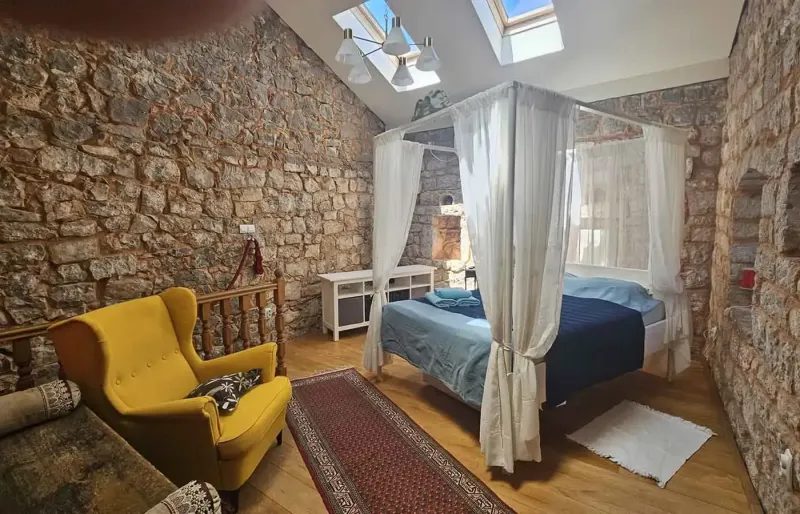 Helles Schlafzimmer mit Himmelbett, Steinw&auml;nden und Dachfenstern
