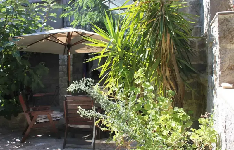 Schattiger Innenhof mit Tisch, St&uuml;hlen, Sonnenschirm und Pflanzen