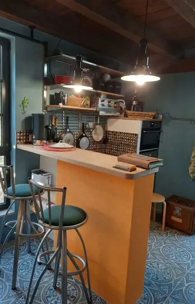 Cozy kitchen with bar, stools, open shelves and warm lighting