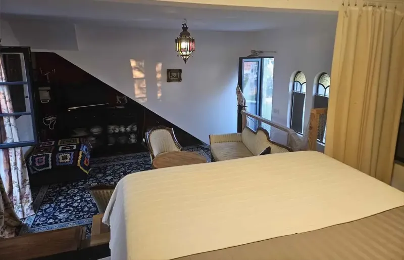 Bedroom overlooking lounge area with sofa, rugs and sloped ceiling