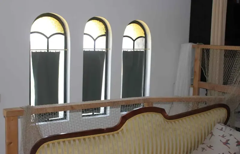 Gallery with sofa, wooden railing and three narrow arched windows