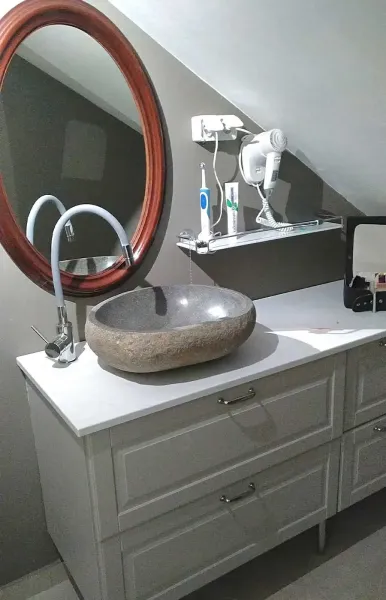 Vanity with stone basin, round mirror and shelf with hairdryer