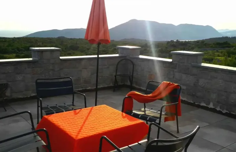 Rooftop terrace with table, chairs, parasol and wide mountain view