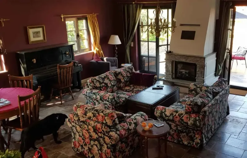 Large living room with fireplace, floral sofas, piano and dining table