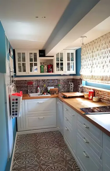 Modern kitchen with white cabinets, wooden countertops and patterned tiles