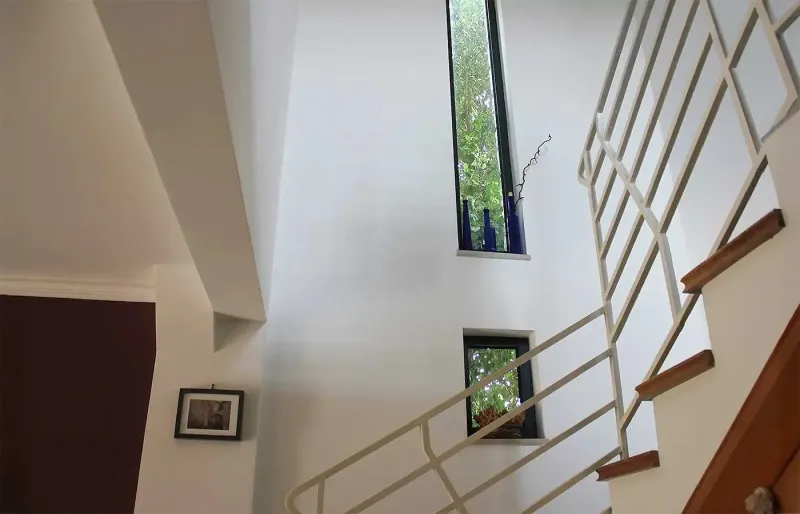 Open stairwell with white walls, wooden steps and narrow windows
