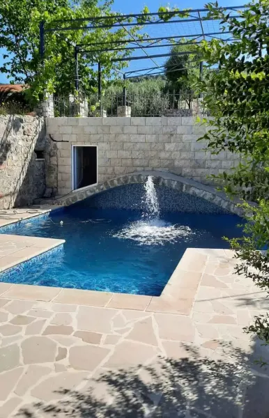 Natural pool with fountain, stone walls and sunny terrace