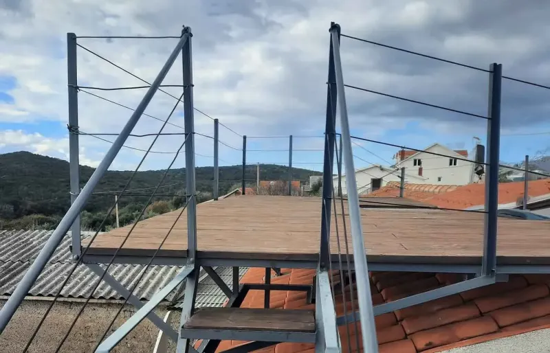 Wooden rooftop terrace with railing and views of hills and rooftops