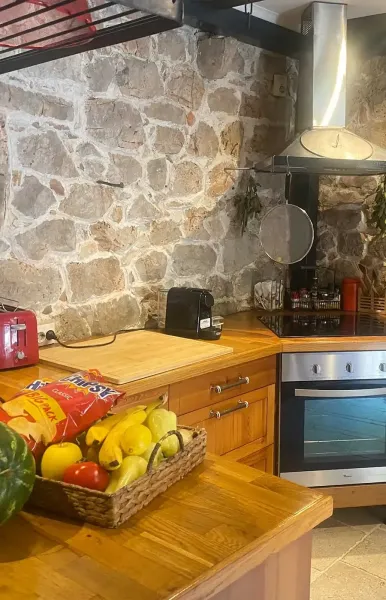 Rustikale K&uuml;che mit Holzarbeitsfl&auml;chen, Steinwand, Backofen und frischem Obst