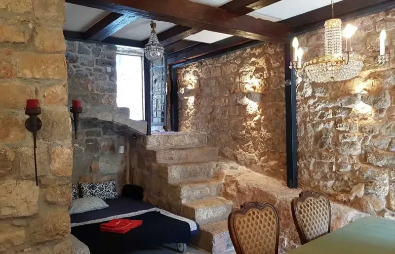 Historischer Essbereich mit Steinw&auml;nden, Kronleuchter, Treppe und Tagesbett