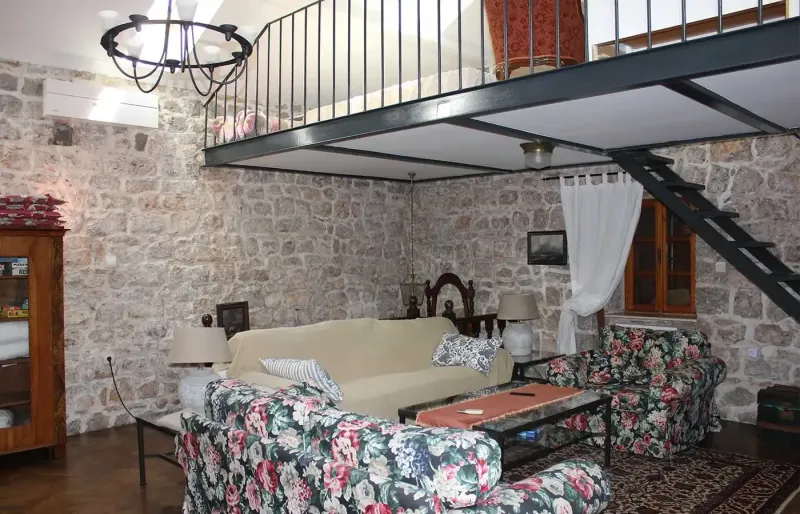 Spacious living area with natural stone walls, mezzanine, staircase and cozy seating